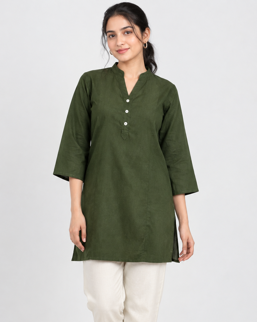 A woman modeling an olive green short-sleeve kurta with a buttoned neckline, paired with off-white cropped pants and beige sandals, against a light gray studio background.